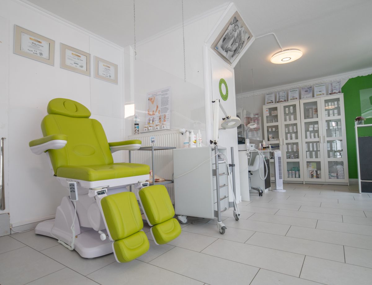 An aesthetic clinic treatment room with a procedure chair, magnifying lamp and product display cabinets