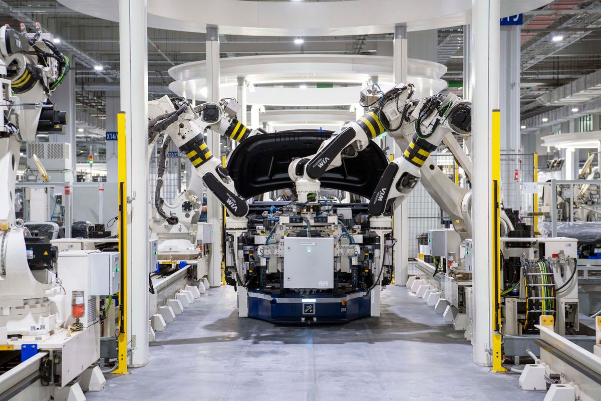 Industrial robot arms working on a car body in an automated assembly plant
