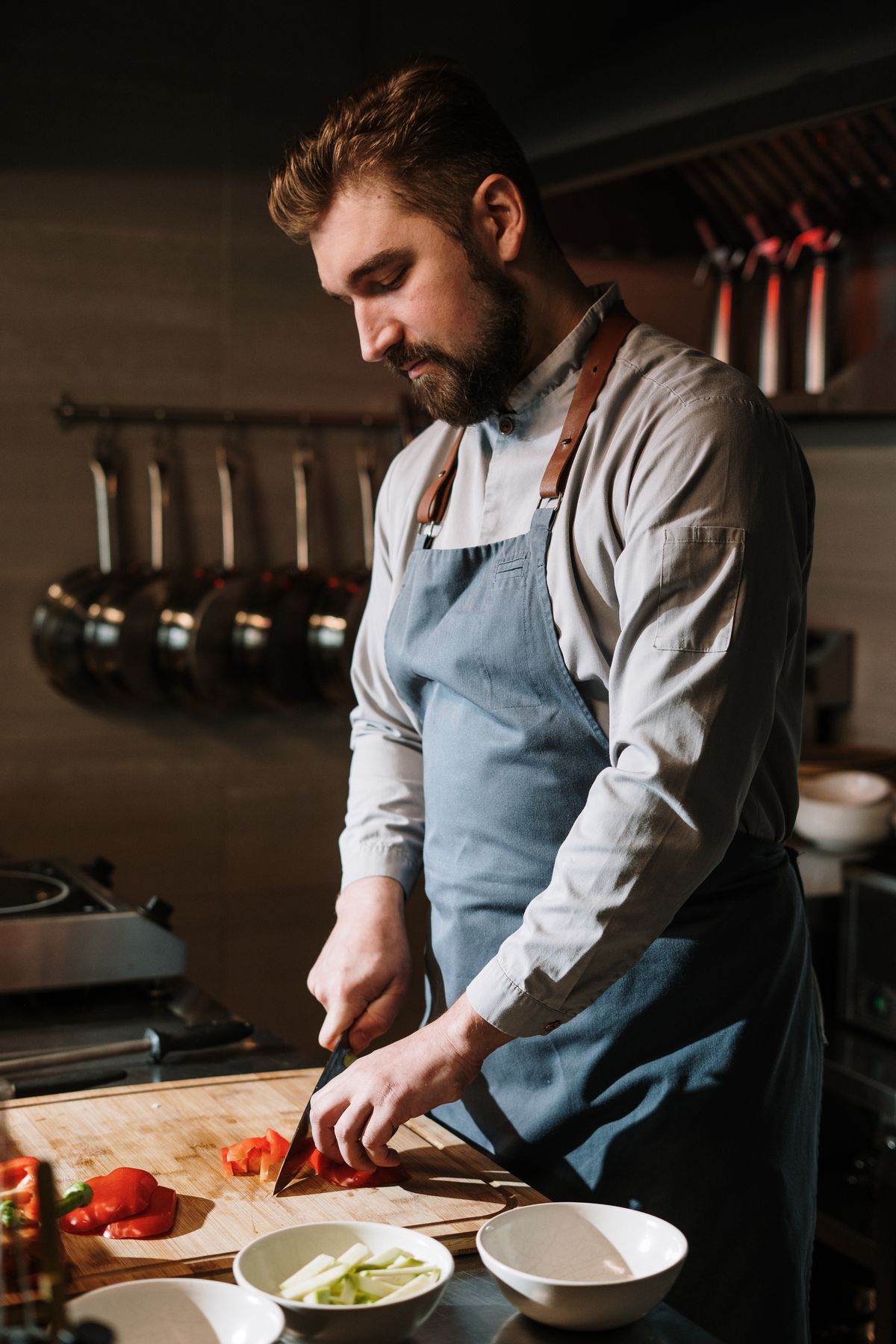 A chef preparing vegetables on a cutting board in a commercial kitchen