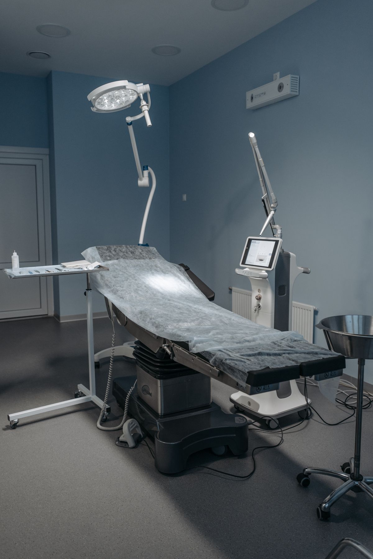 A sterile procedure room with an operating table, surgical light and a laser console
