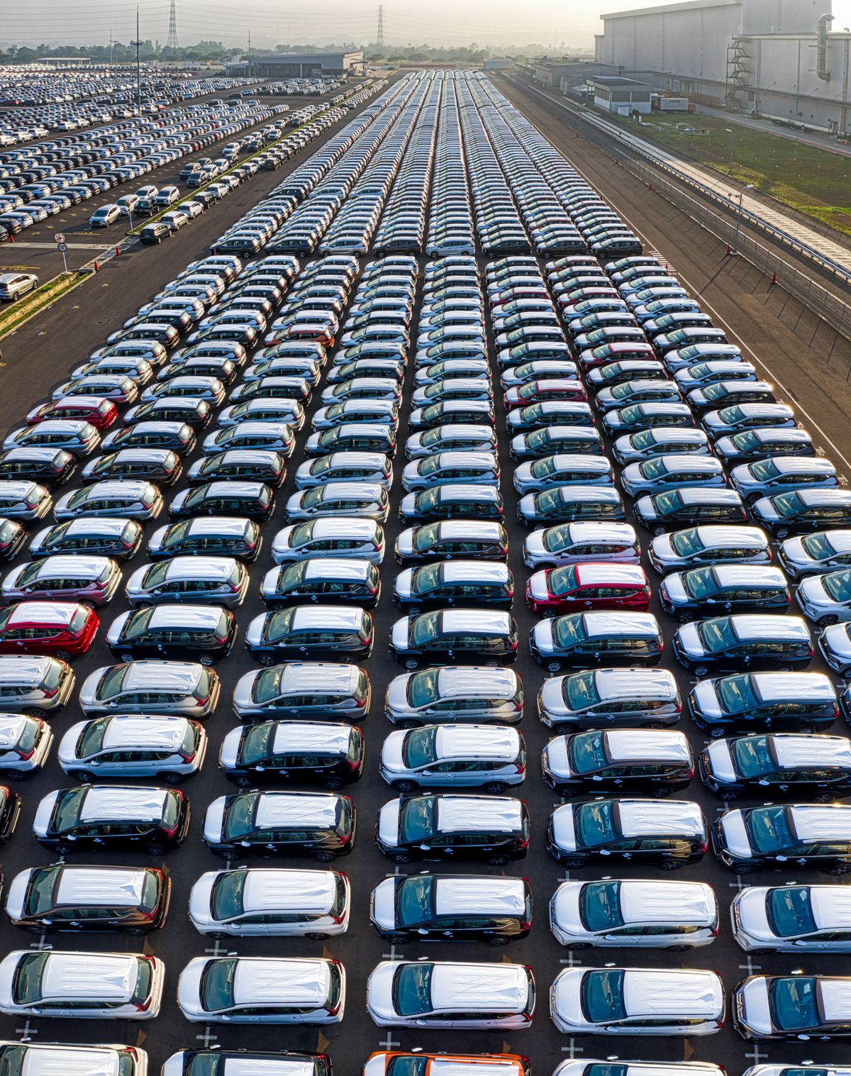 Aerial view of rows of newly manufactured cars parked at a production facility