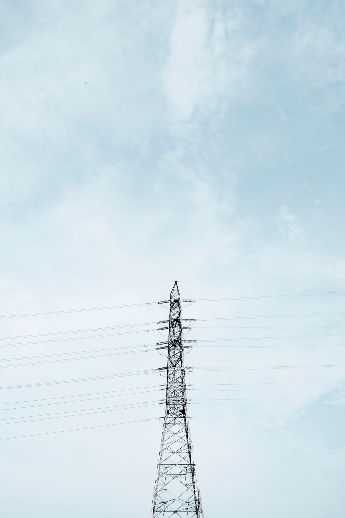 A high-voltage electricity transmission tower carrying power lines against the sky