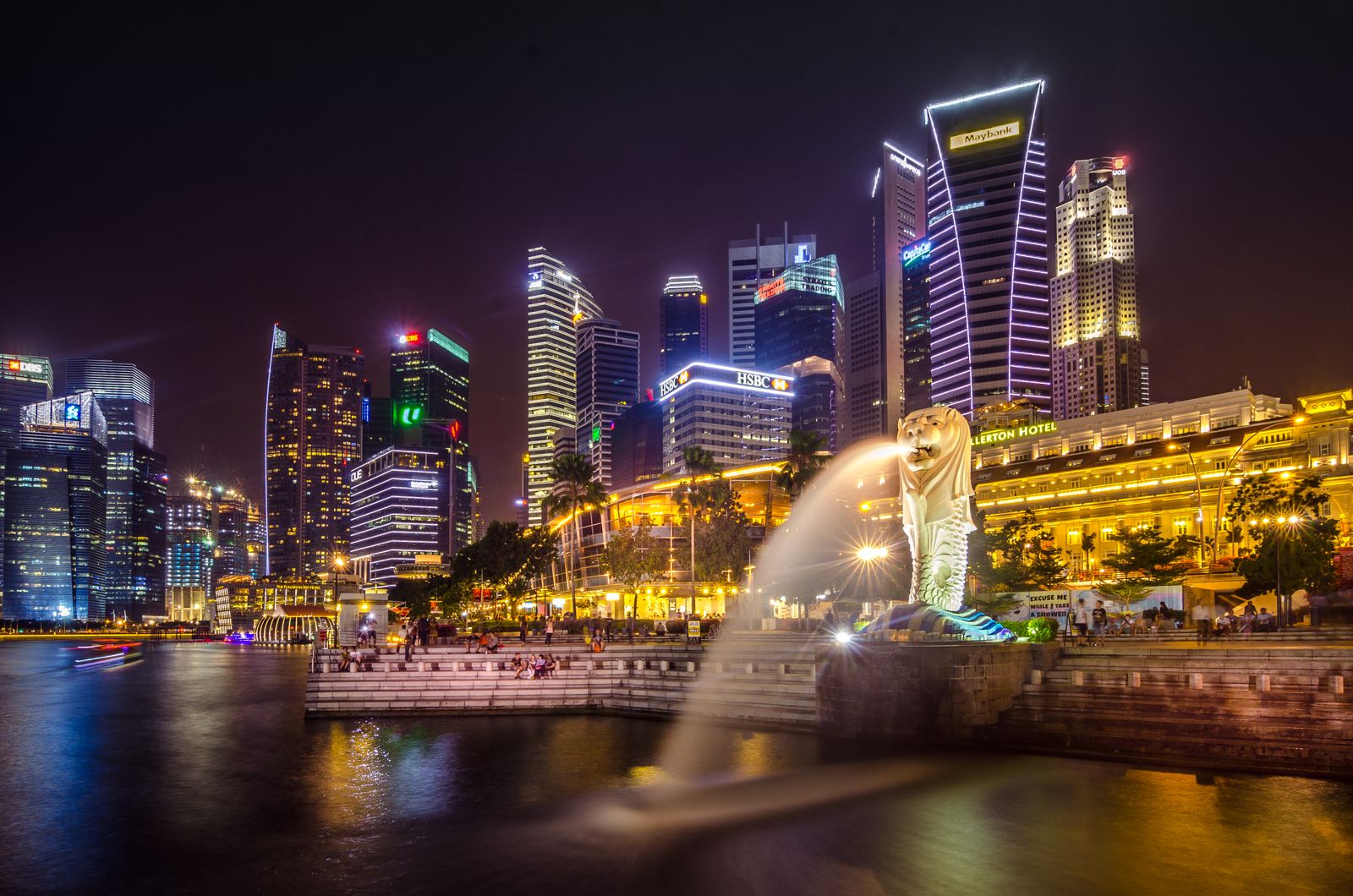 Singapore's central business district skyline at night behind the Merlion